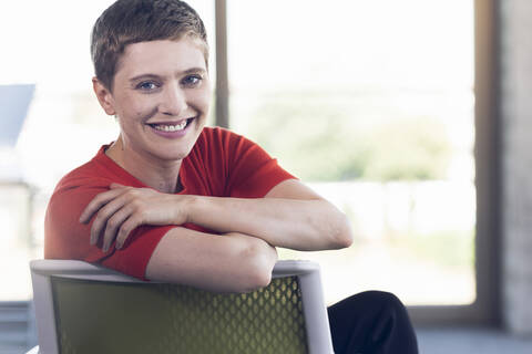 Portrait of smiling businesswoman sitting on chair in office stock photo