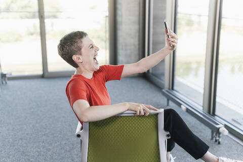 Unbeschwerte Geschäftsfrau mit Smartphone im Büro, lizenzfreies Stockfoto