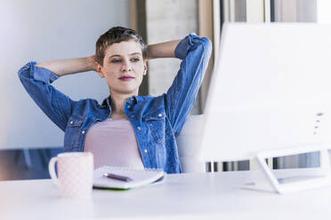 Relaxed businesswoman sitting at desk in office - UUF21167