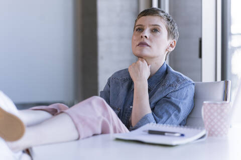 Businesswoman thinking at desk in office stock photo