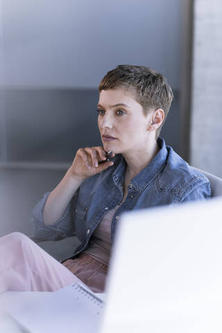 Geschäftsfrau denkt am Schreibtisch im Büro nach, lizenzfreies Stockfoto