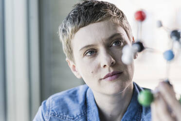 Woman looking at molecule model - UUF21185