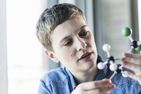 Frau schaut auf Molekülmodell, lizenzfreies Stockfoto