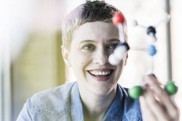 Happy woman looking at molecule model - UUF21188