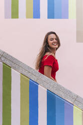 Young woman standing on staircase during sunny day - DLTSF01128