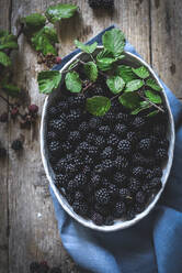 Von oben schmackhafte frische Brombeeren in einer Schale auf Holzuntergrund mit blauer Serviette serviert - ADSF14545