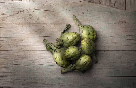 Fresh artichoke on old cracked wooden surface indoors stock photo