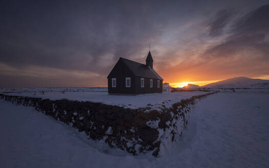 Amazing Northern Landschaft mit kleinen Kirche auf Wüste schneebedeckten Gelände gegen bewölkten Abendhimmel bei Sonnenuntergang in Island gelegen - ADSF14607