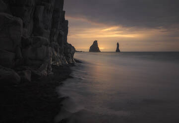 Famous unusual black sand beach and rocky coastline at sunset in Iceland - ADSF14618