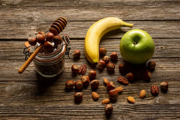 Apfel und Banane mit Nüssen auf Holztisch - ADSF14639