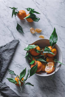 Orangefarbene Mandarinen in keramischer Zierschale auf Marmortisch - ADSF14698