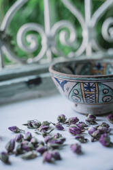 Kleine getrocknete Blumenknospen und eine dekorative Schale am offenen Fenster in einem traditionellen arabischen Haus in Marrakesch, Marokko - ADSF14715