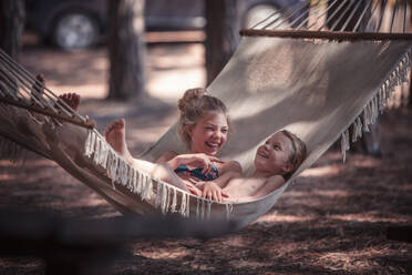 Glückliche Mädchen entspannen auf Hängematte am Strand im Sommer - DHEF00342