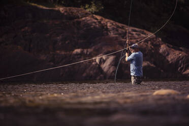 Fly fisherman casting with two handed rod in river - DHEF00348