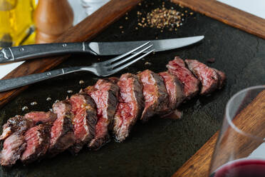 Draufsicht auf medium rare Steakscheiben auf dem Tisch mit Gabel und Messer im Restaurant - ADSF14757