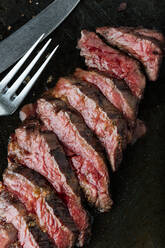 Draufsicht auf medium rare Steakscheiben auf dem Tisch mit Gabel und Messer im Restaurant - ADSF14758