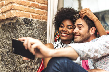 Close-up of mid adult man taking selfie with girlfriend in coffee shop - EHF00822