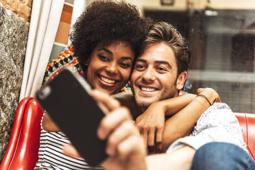 Close-up of happy girlfriend embracing boyfriend taking selfie in restaurant - EHF00826