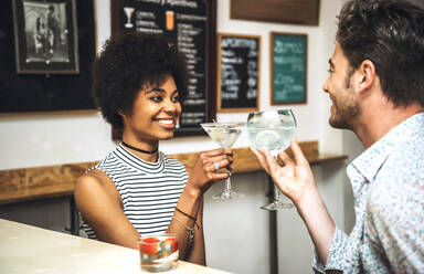 Happy couple toasting drinks while sitting at bar counter - EHF00839