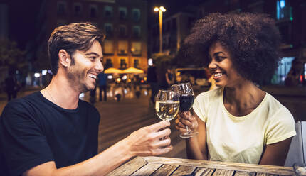 Fröhliches Paar, das sich anschaut, während es mit Weingläsern auf einen gemeinsamen Abend anstößt - EHF00849