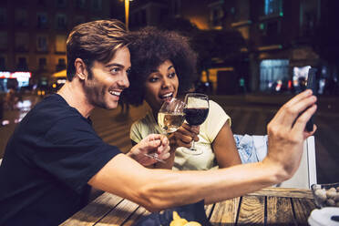 Man taking selfie with girlfriend while toasting wine with her at date night - EHF00852