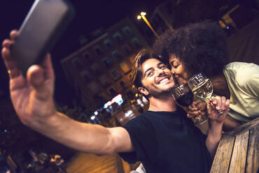 Woman kissing boyfriend taking selfie at date night - EHF00853