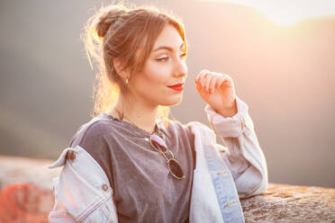 Fröhliche junge Frau in trendigem Freizeitoutfit lächelt und schaut weg an einem sonnigen Tag - ADSF14780