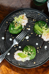 Von oben leckerer appetitlicher Rosenkohl mit Sahnesoße und Kräutern auf schwarzem Teller im Restaurant - ADSF14829