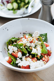 Von oben saftig appetitlich Salat von reifen roten geschnittenen Tomaten grünen Samen und Käse in weißen Teller im Restaurant - ADSF14836