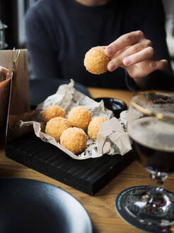 Crop weiblich hält leckeren Käse Ball mit Mozzarella-Füllung beim Sitzen am Tisch im Café - ADSF14849