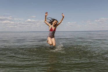 Kleines Mädchen springt im Sommer am Strand ins Wasser - OGF00496