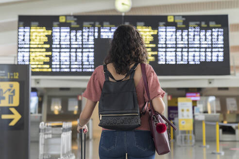 Junge Frau prüft ihren Flug in der Zeittafel am Flughafen - MTBF00660