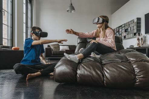 Freunde, die zu Hause sitzend durch Virtual-Reality-Simulatoren gestikulieren - MFF06098