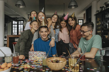 Happy friends standing by birthday boy at dining table - MFF06128