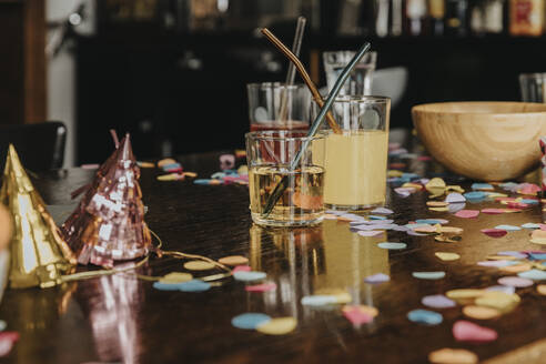 Close-up of drinks with party hats and confetti on dining table at home - MFF06142