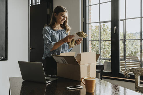 Girl holding scarf received through online shopping at home - MFF06148