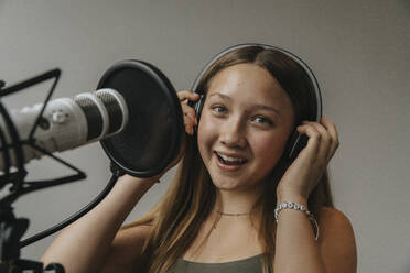 Nahaufnahme eines glücklichen Teenagers, der in einem Aufnahmestudio an der Wand singt - MFF06171