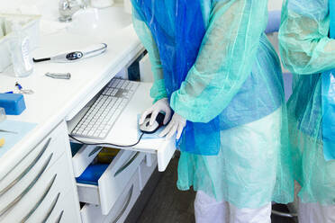 Doctor and assistant in protective suit working at dentist office - JCMF01260