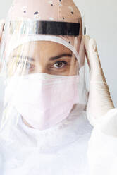 Dentist in protective suit adjusting face mask at office - JCMF01280