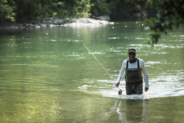 Fisherman wading through green river - DHEF00367