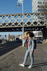 Afro-Frau spricht über Handy, während sie auf dem Bürgersteig in der Stadt steht - BOYF01455
