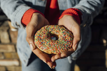 Nahaufnahme einer jungen Frau, die einen Donut in den Händen hält - BOYF01469