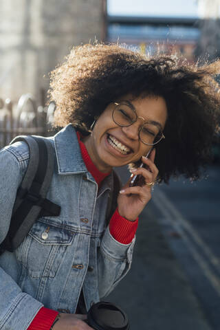 Close-up of cheerful afro woman talking over smart phone in city stock photo