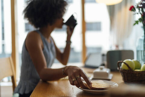 Junge Frau beim Frühstück auf dem Tisch zu Hause, lizenzfreies Stockfoto