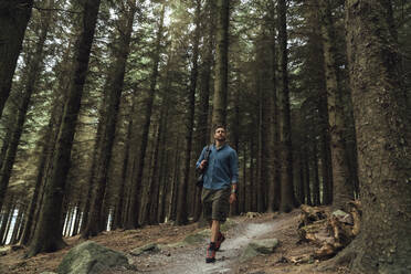 Männlicher Wanderer auf einem Wanderweg inmitten von Bäumen in einem Waldgebiet - BOYF01574