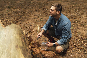 Männlicher Biologe schaut weg, während er Bodenproben im Wald nimmt - BOYF01588