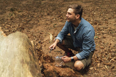 Male biologist looking away while taking samples of land in forest - BOYF01588