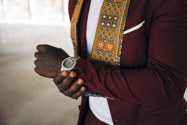 Junger Mann trägt traditionellen Kente-Anzug, während er in einem Gebäude steht - MPPF01069