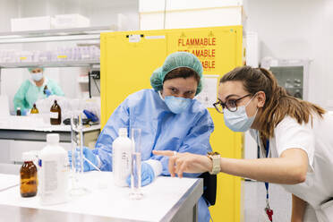 Female pharmacists discussing while preparing medicines in laboratory - DGOF01262