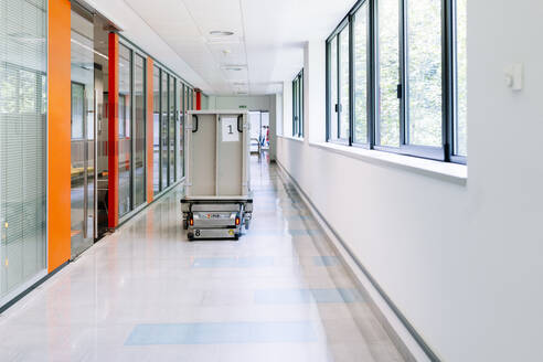 Roboterwagen mit Metallbehälter, der sich im Krankenhausflur bewegt - DGOF01289
